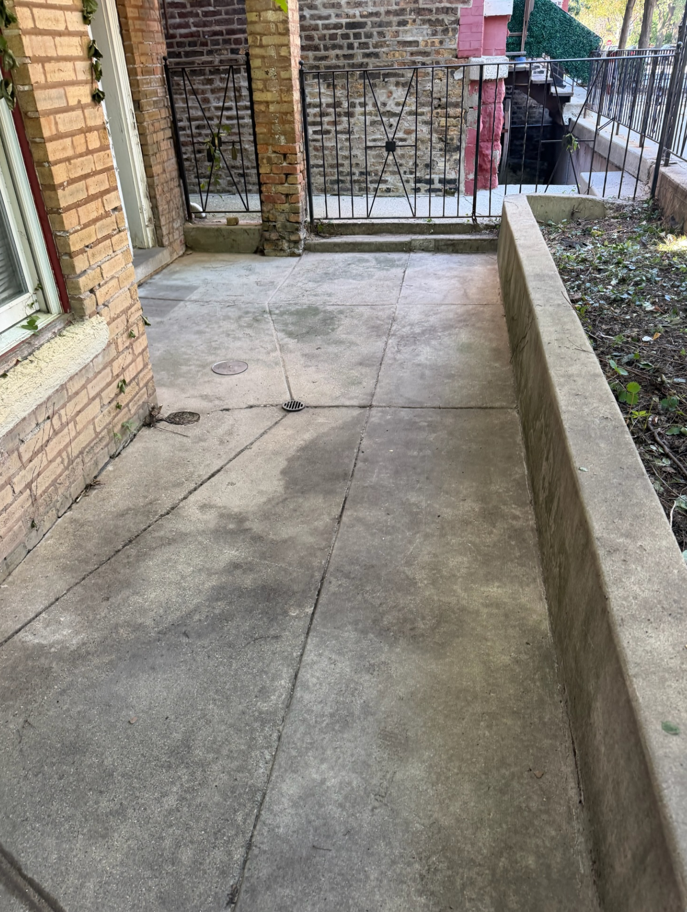 The same walkway and patio cleared of vegetation, with clean exposed concrete