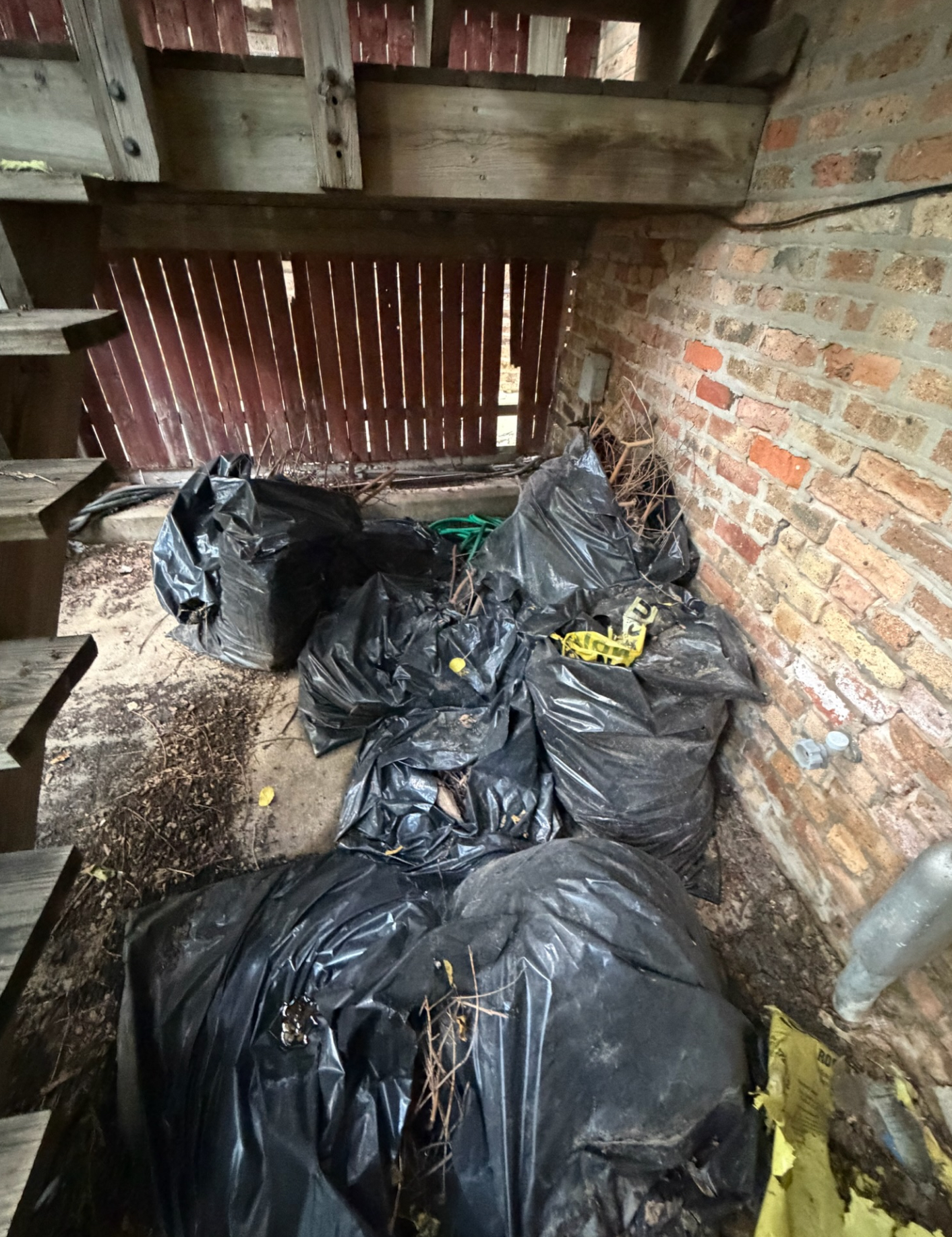 Patio area filled with black bags of collected yard debris awaiting haul-away